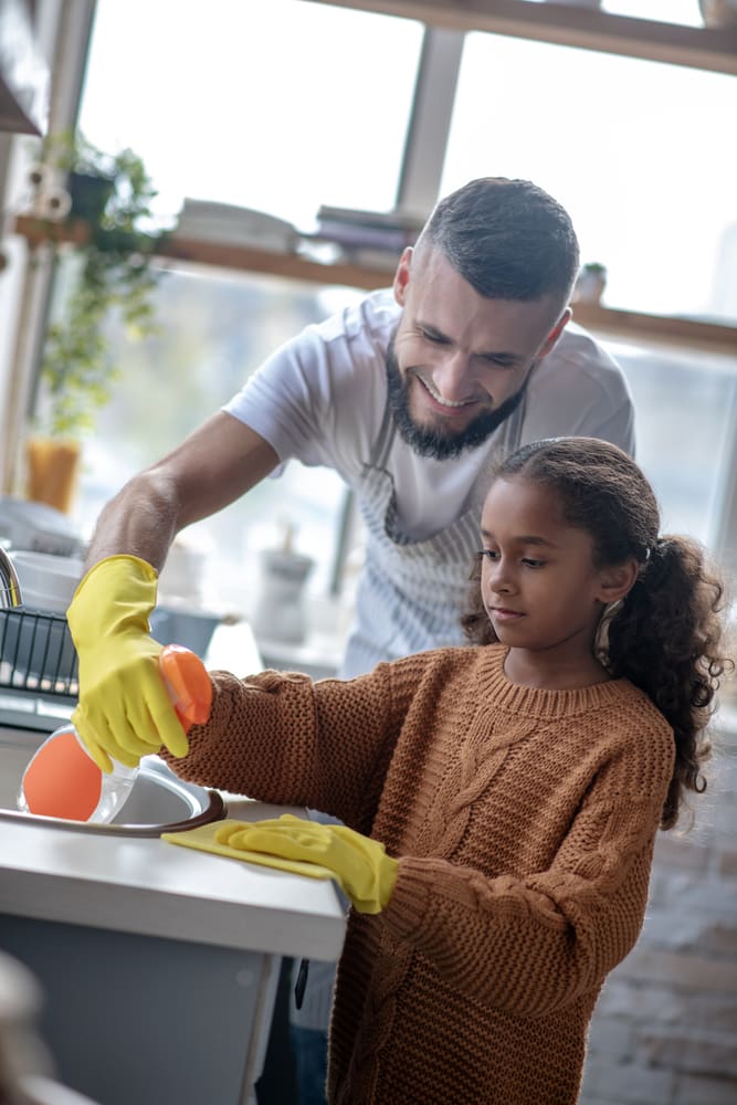 Dad washing dishes to train his child how to do it well
